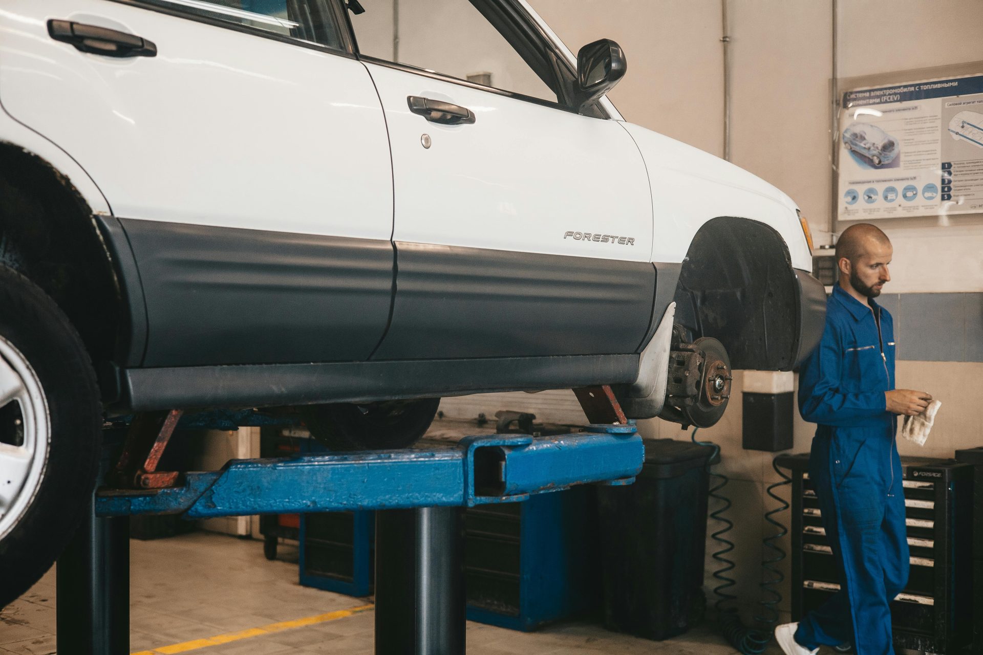 Mecánico evaluando un automóvil en un elevador para mantenimiento en un taller automotriz.